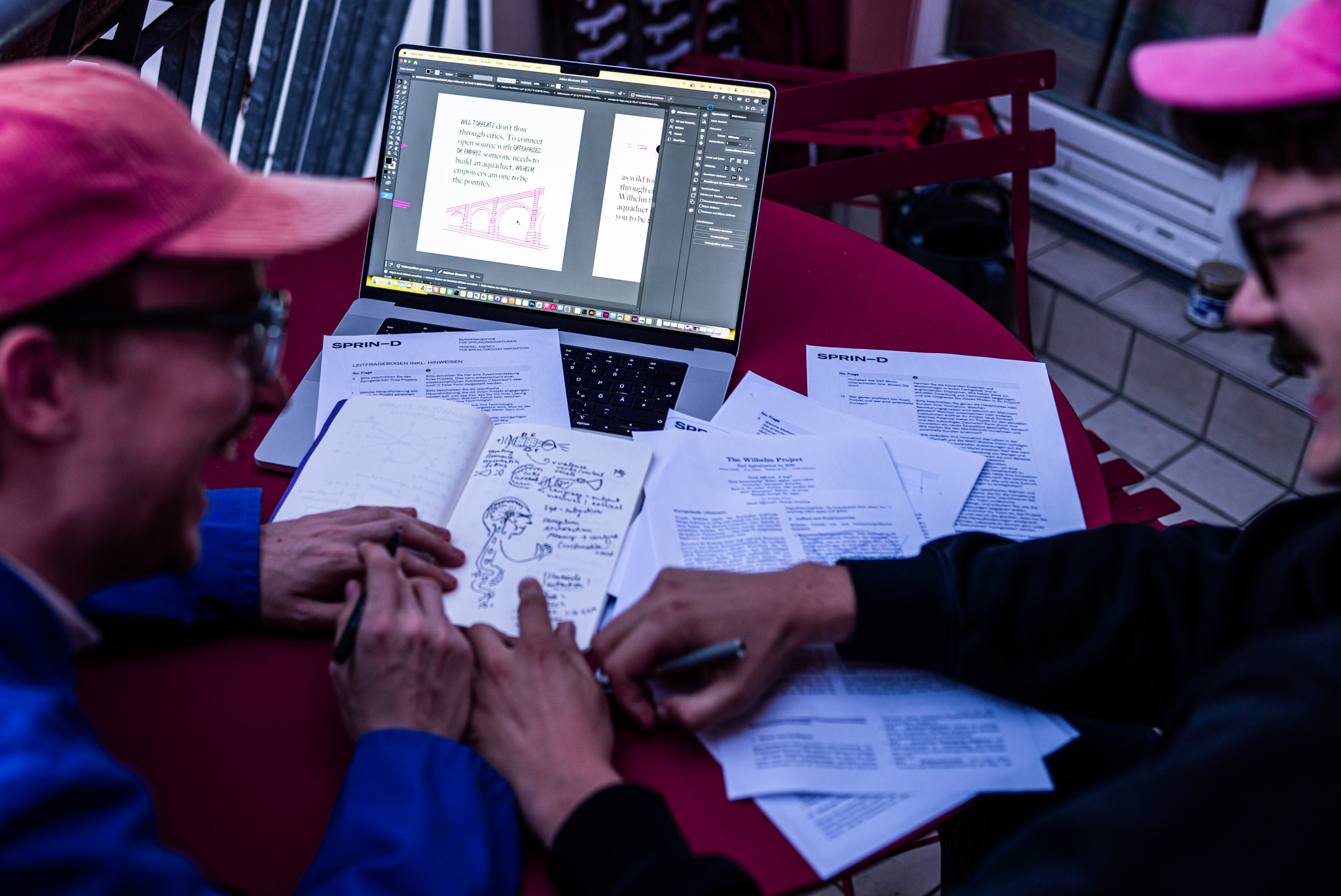 The Wilhelm Collective - the two founders sketching Wilhelm at a café table